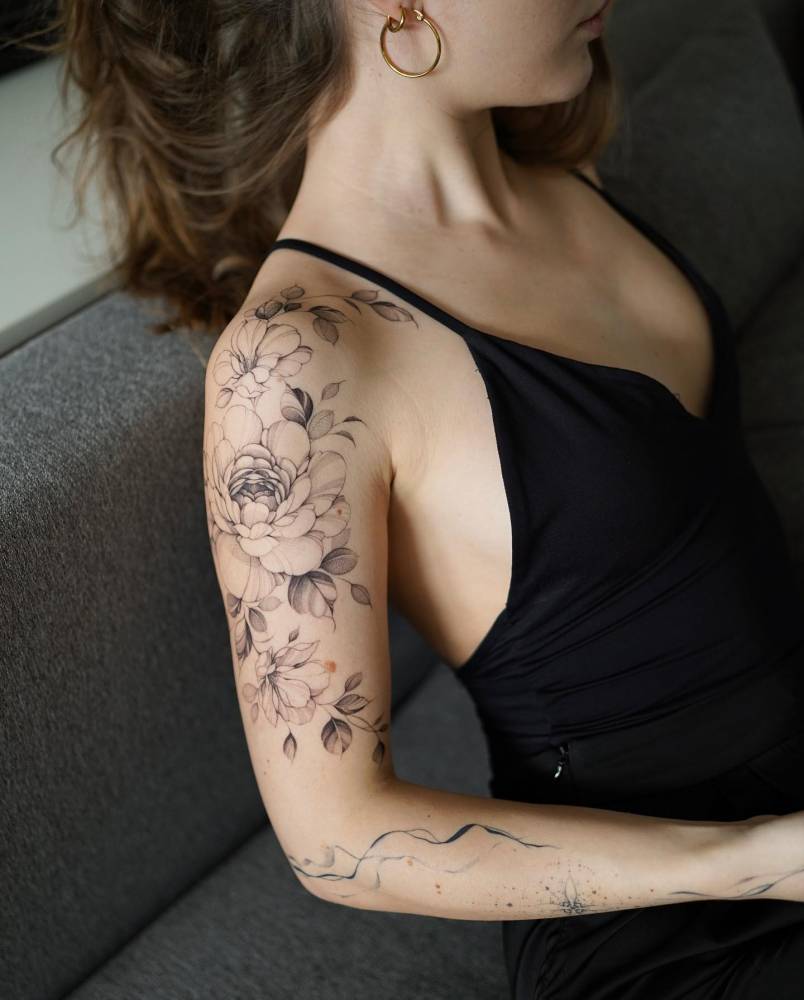 Illustrative style peony and magnolia tattoo located on the upper arm.
