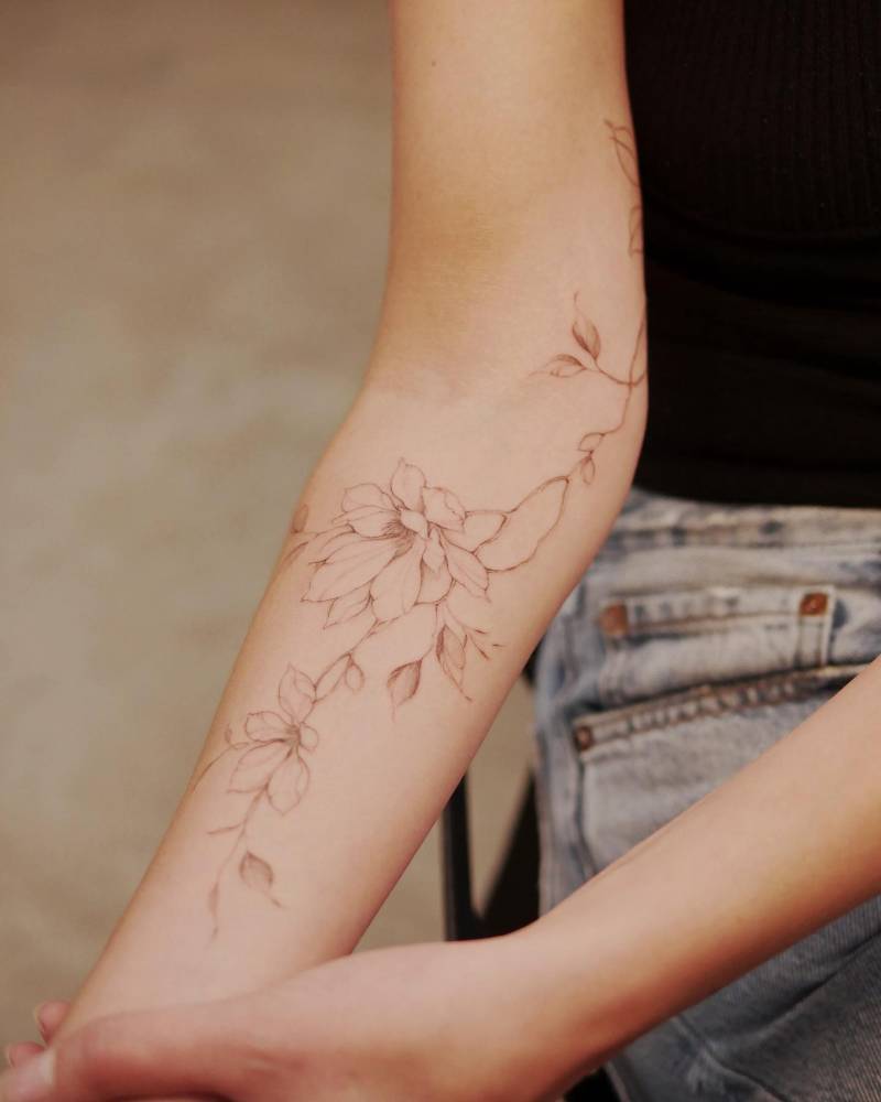 Magnolia flowers tattoo located on the inner forearm.