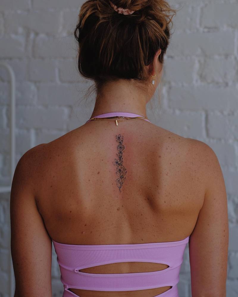 Fine line style floral design tattooed on the upper back.