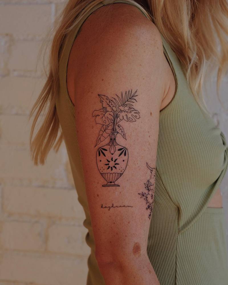 Plant vase tattoo located on the upper arm.