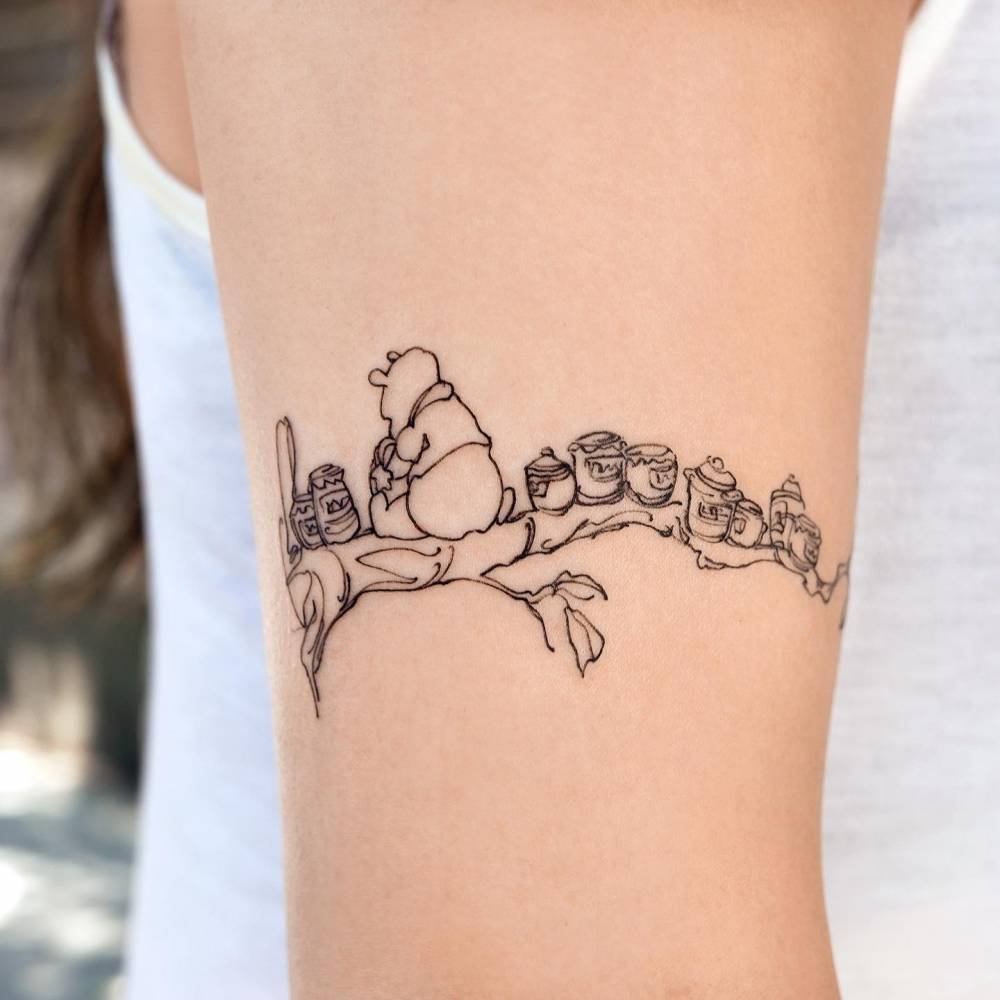 Sketch work style Pooh Bear tattoo located on the upper arm.