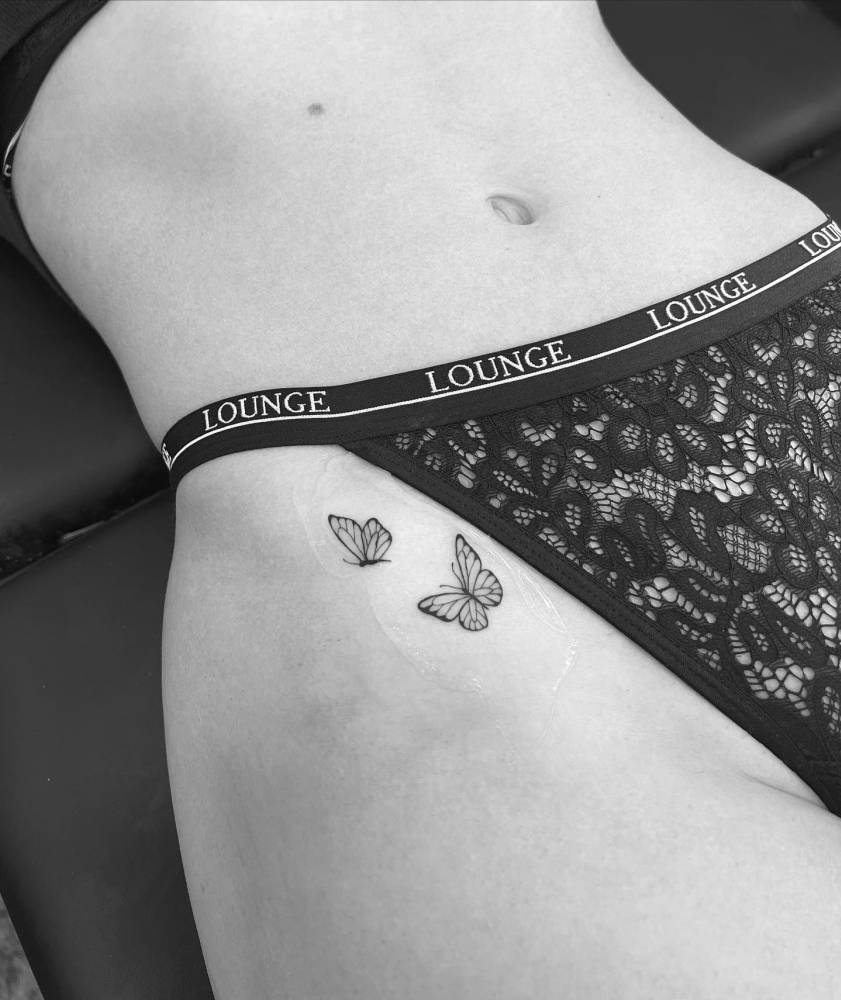 Fine line style butterfly couple tattoo located on the pelvis.