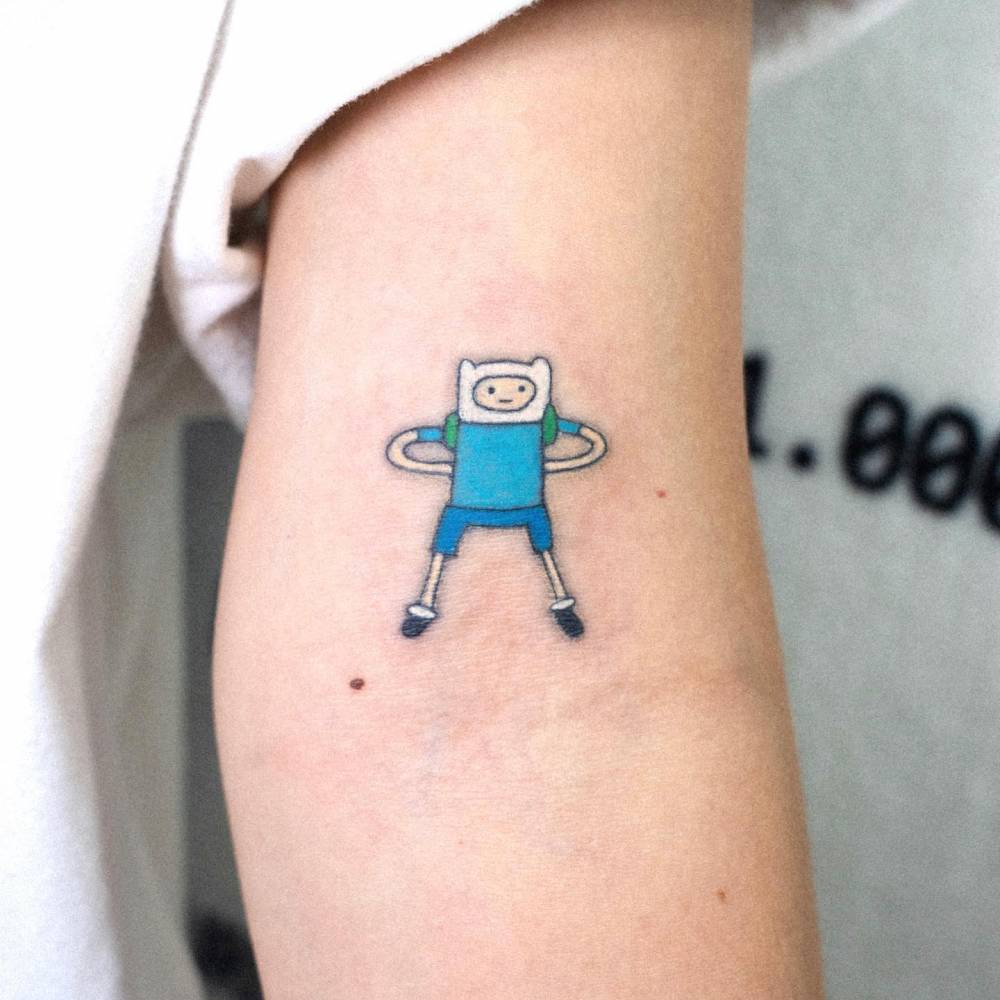 Finn the Human tattoo located on the bicep, cartoon style.
