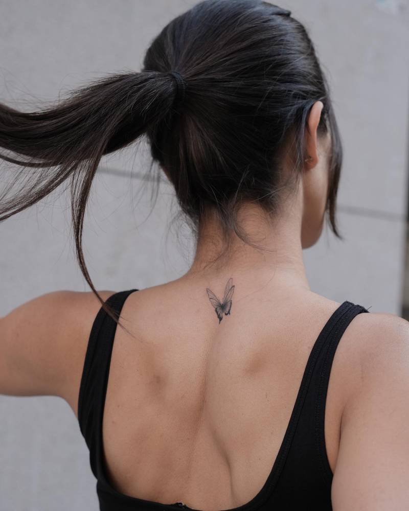 Butterfly tattoo located on the upper back, illustrative style.