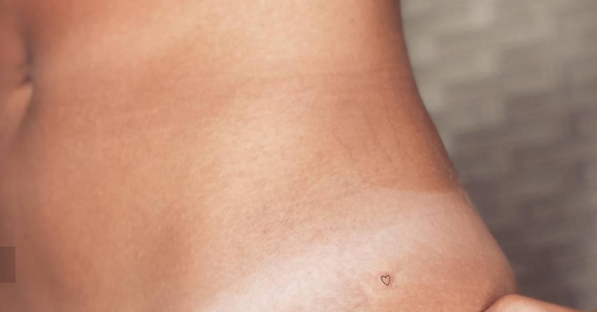 Tiny minimalistic heart tattoo placed on the hip.