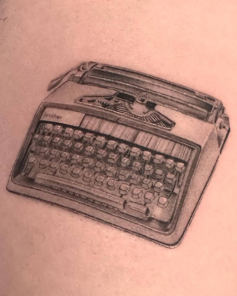 Micro-realistic typewriter tattoo placed on the inner forearm.