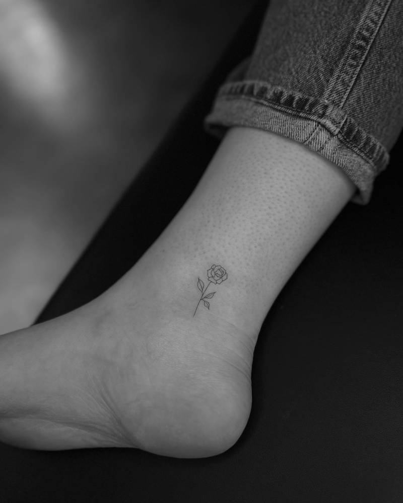Fine line rose tattoo placed on the ankle, minimalistic style.