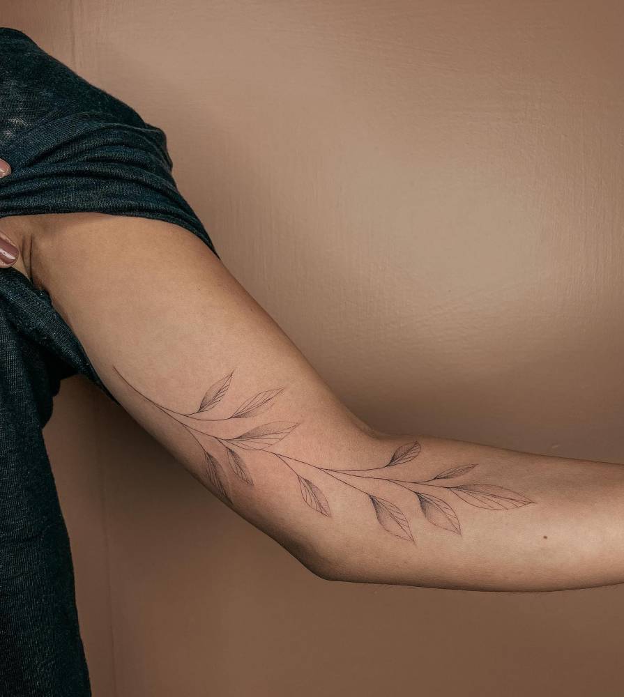Fine line style leaves tattoo located on the arm.