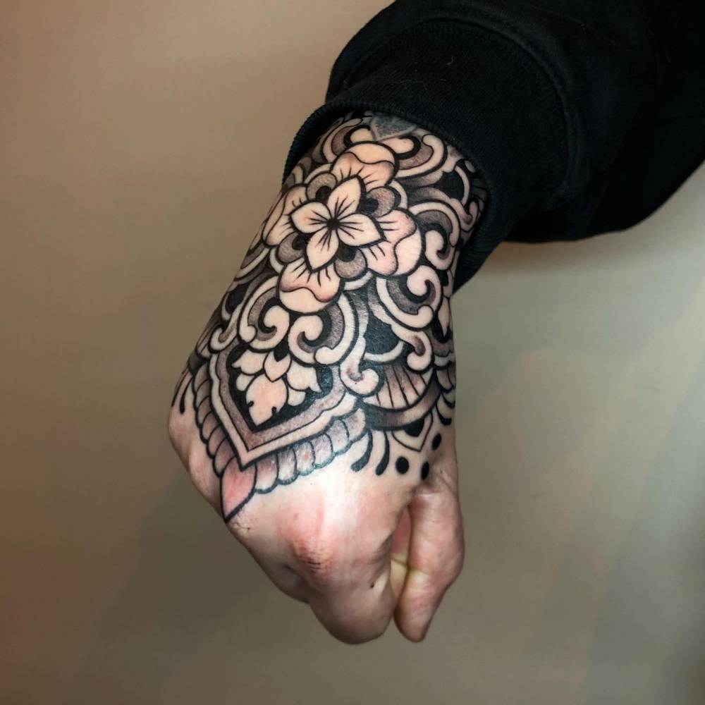 Ornamental flower tattooed on the hand, blackwork style.