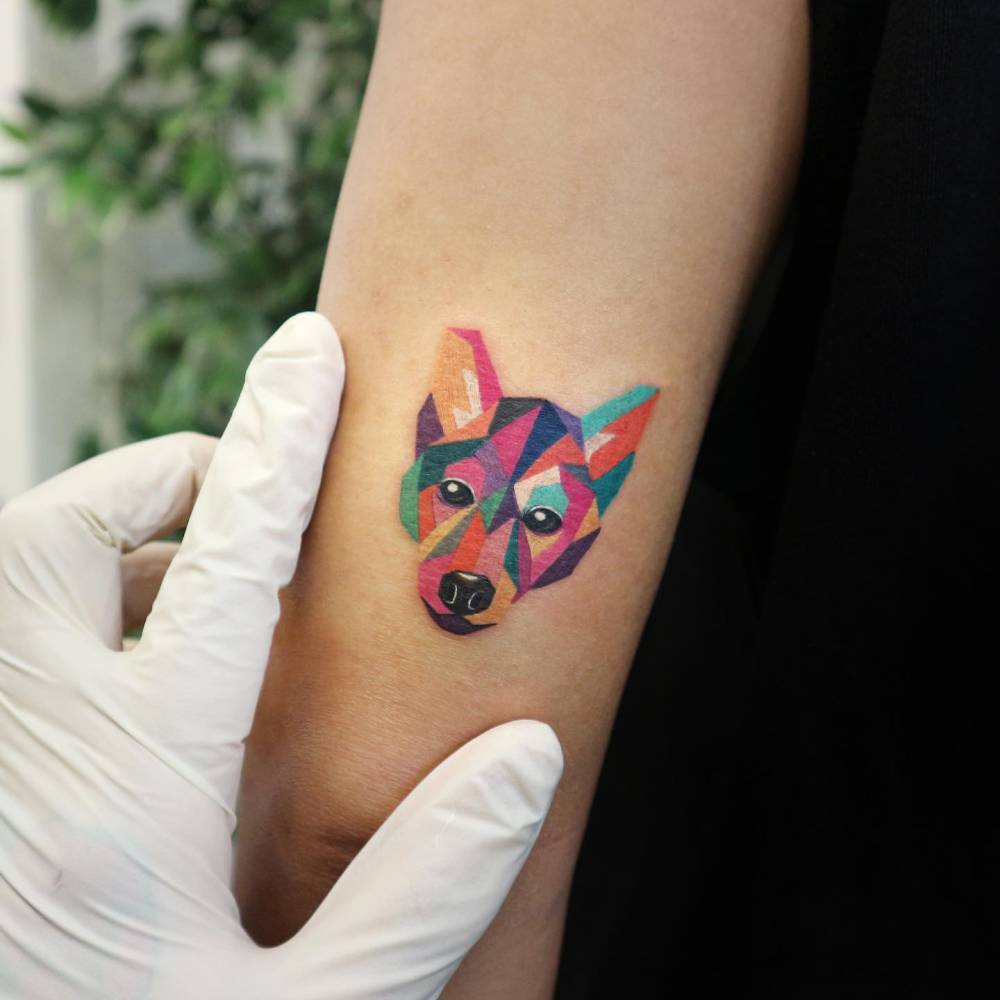 Low poly dog portrait tattoo placed on the tricep.