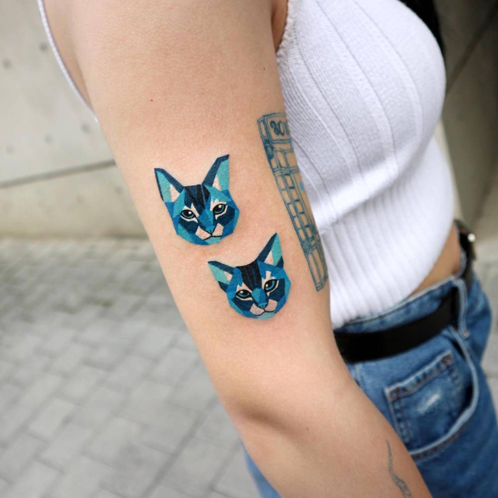 Low poly cat couple portrait tattoo placed on the upper arm.