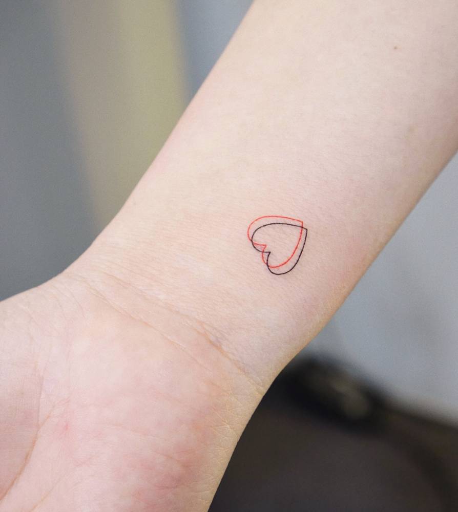 Minimalistic style heart tattoo located on the wrist.