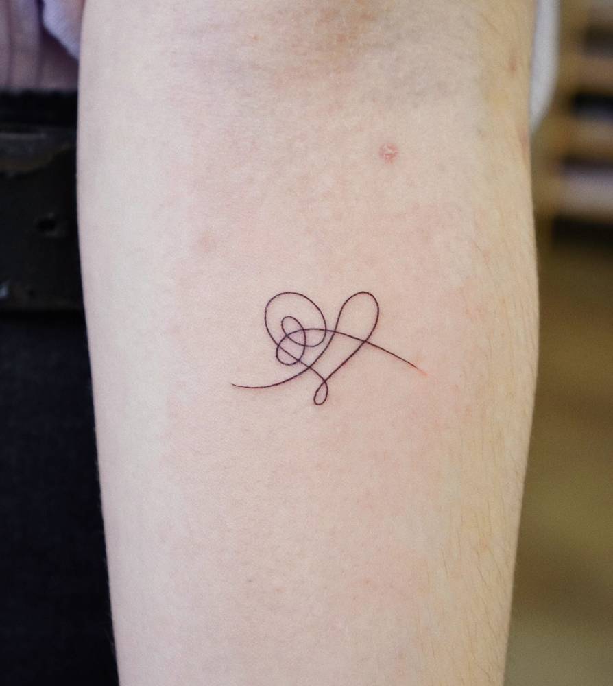 Abstract one line heart tattoo placed on the inner forearm.