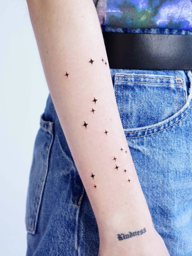 Star collection tattooed on the forearm, minimalistic style.