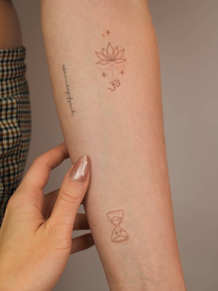 Lotus flower and hourglass tattoos located on the inner forearm.