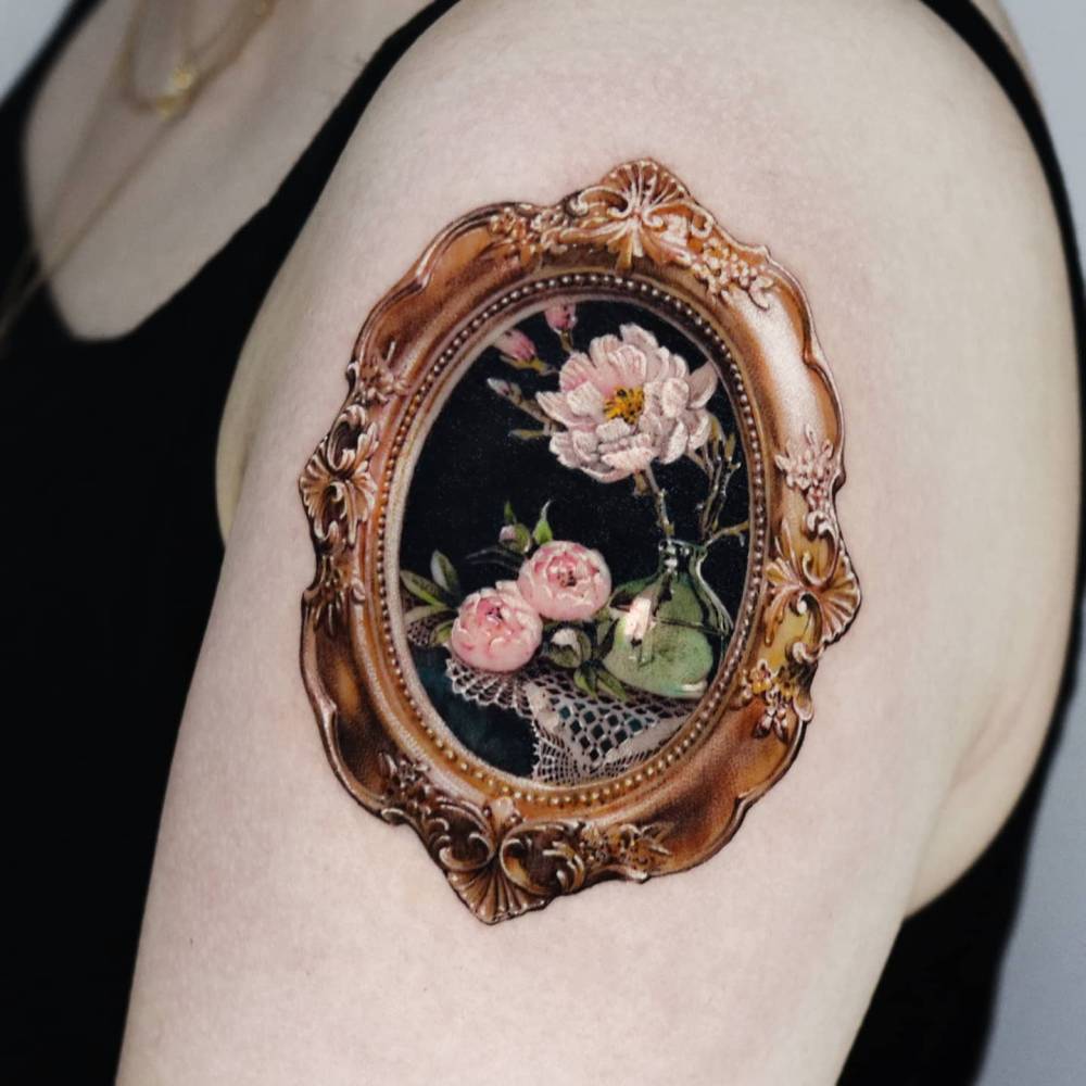 Framed peonies tattoo located on the shoulder, done in micro-realism.