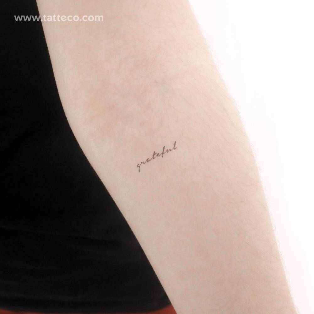 Handwritten font word "grateful" temporary tattoo placed on the inner forearm.