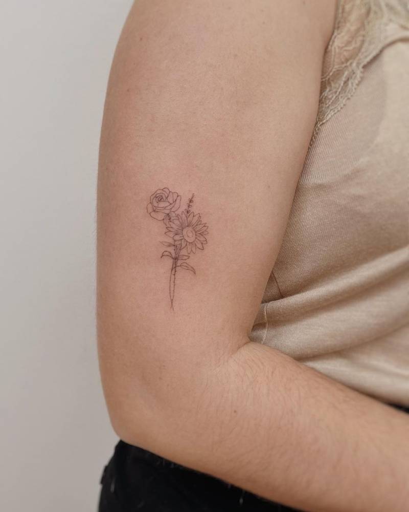 Fine line rose and sunflower tattoo located on the upper arm.
