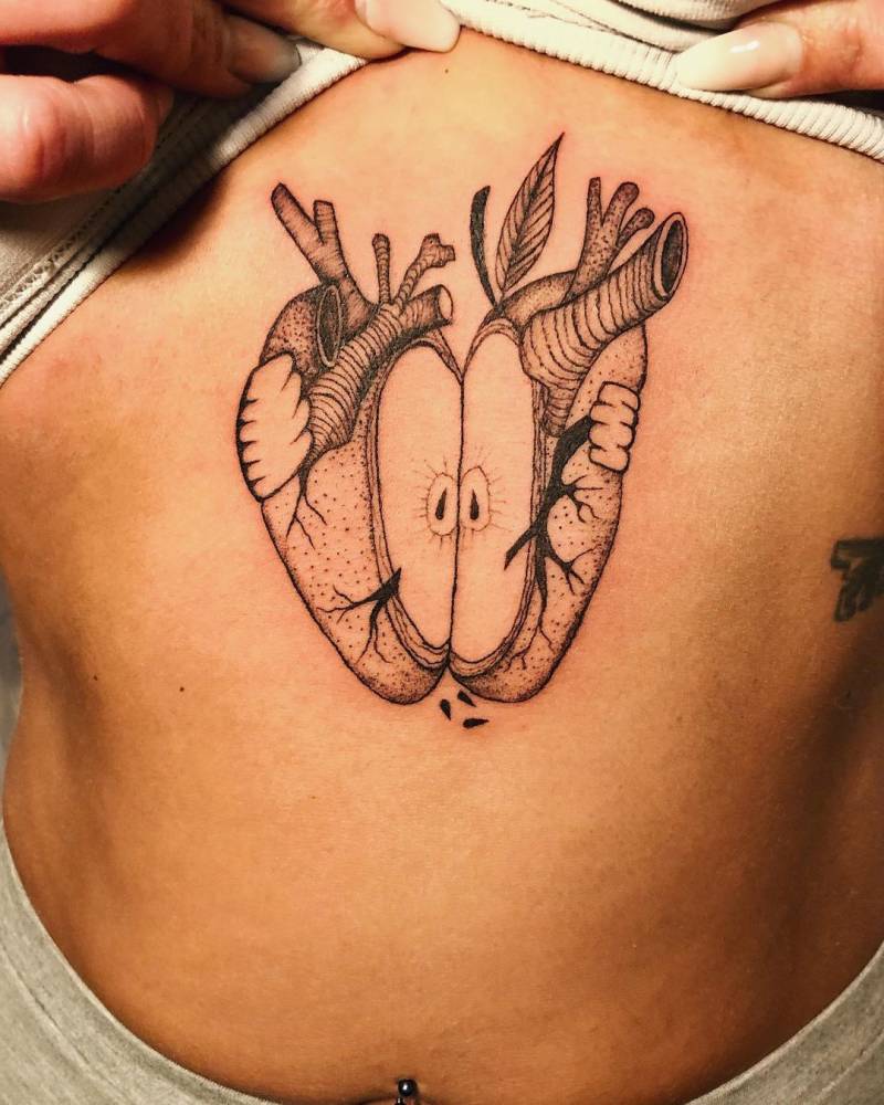 Blackwork style apple heart tattoo on the stomach.