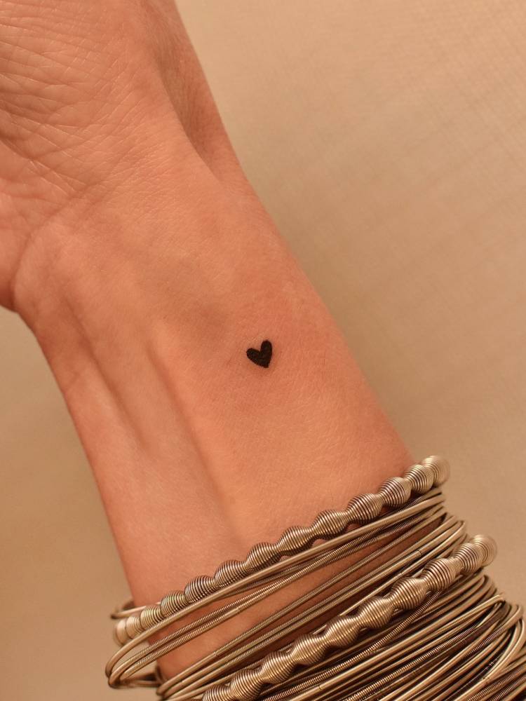 Tiny minimalistic heart tattoo placed on the wrist.