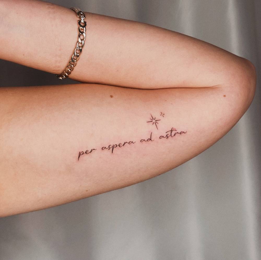"Per aspera ad astra" lettering tattoo located on the inner arm.