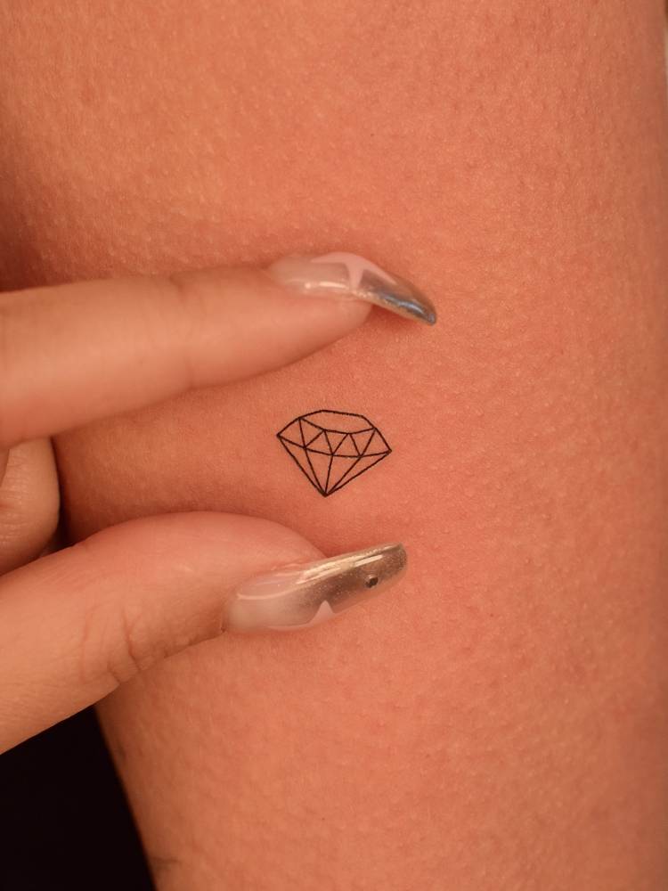 Fine line style micro diamond tattoo placed on the upper arm.
