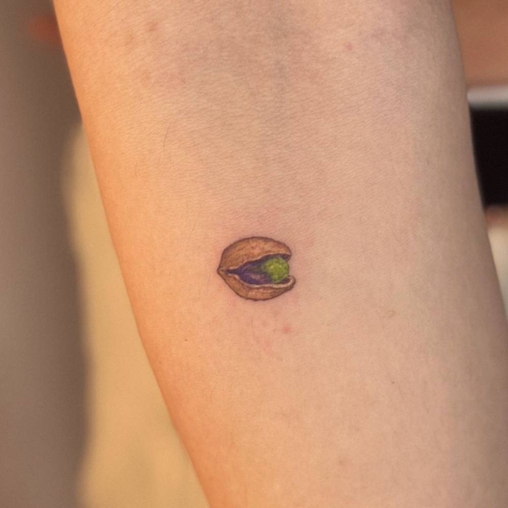 Little pistachio in illustrative style tattooed on the inner forearm.