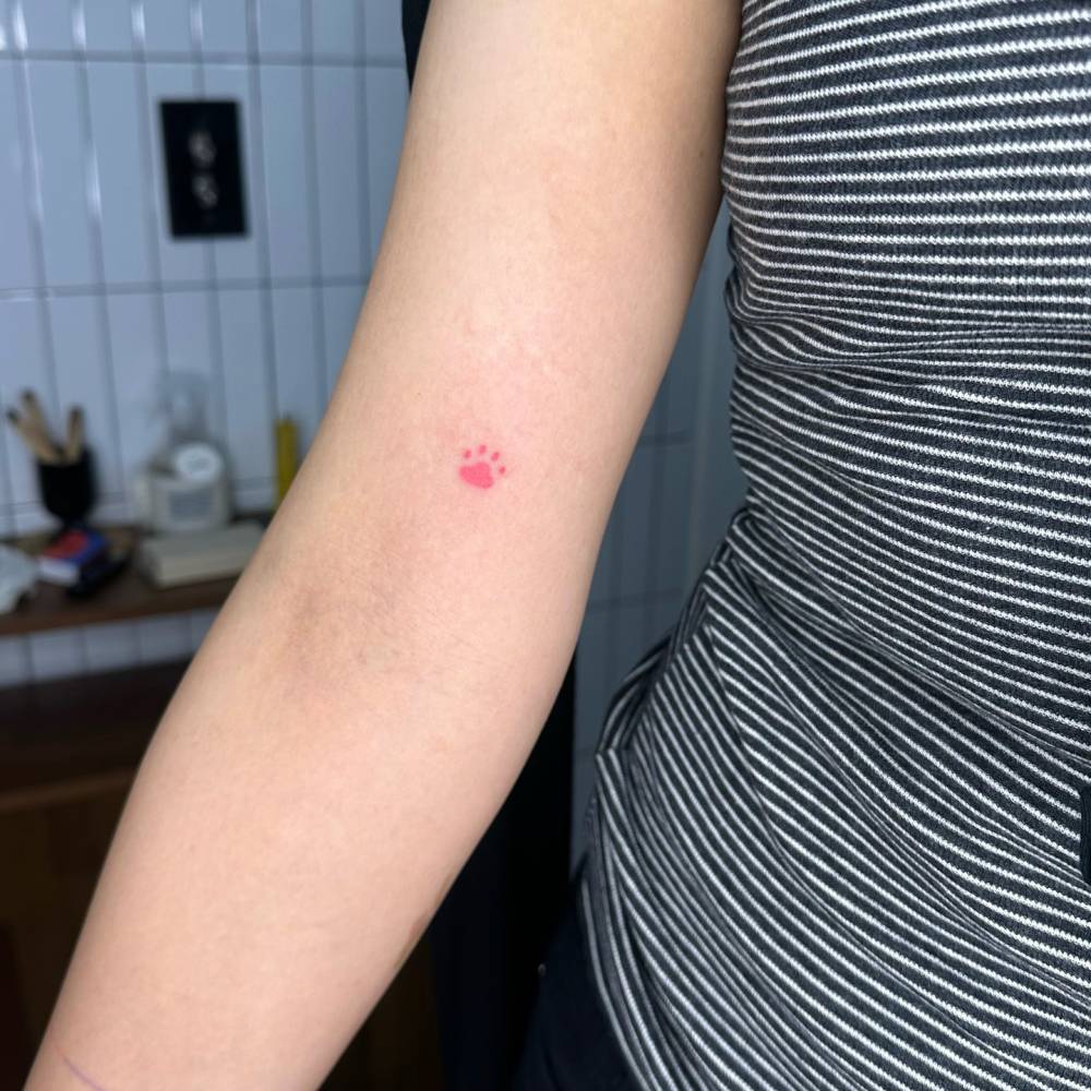 Tiny paw print tattoo in minimalistic style hand poked on the inner arm.