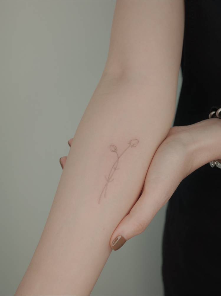 Fine line style little roses tattooed on the inner forearm.