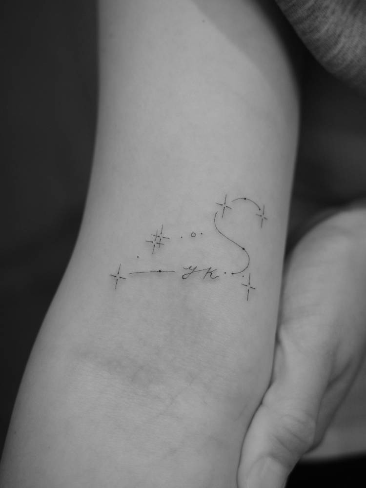 Minimalistic style Leo constellation and initials tattoo located on the inner forearm.