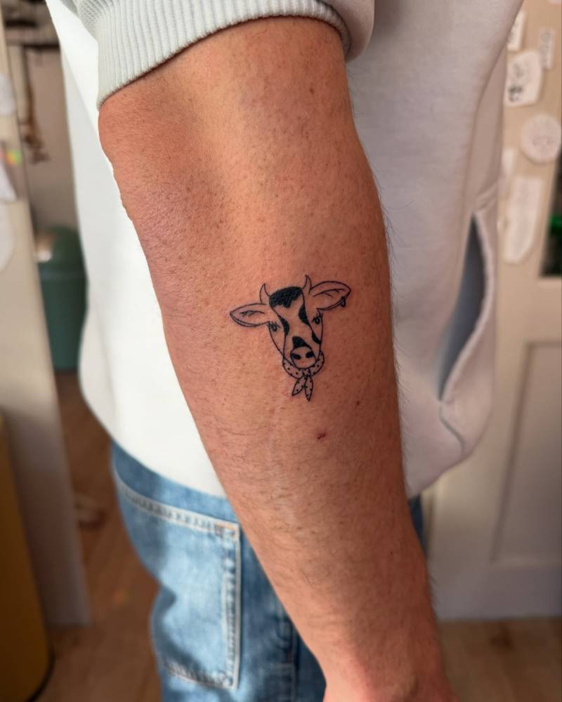 Cow portrait tattoo in illustrative style located on the forearm.
