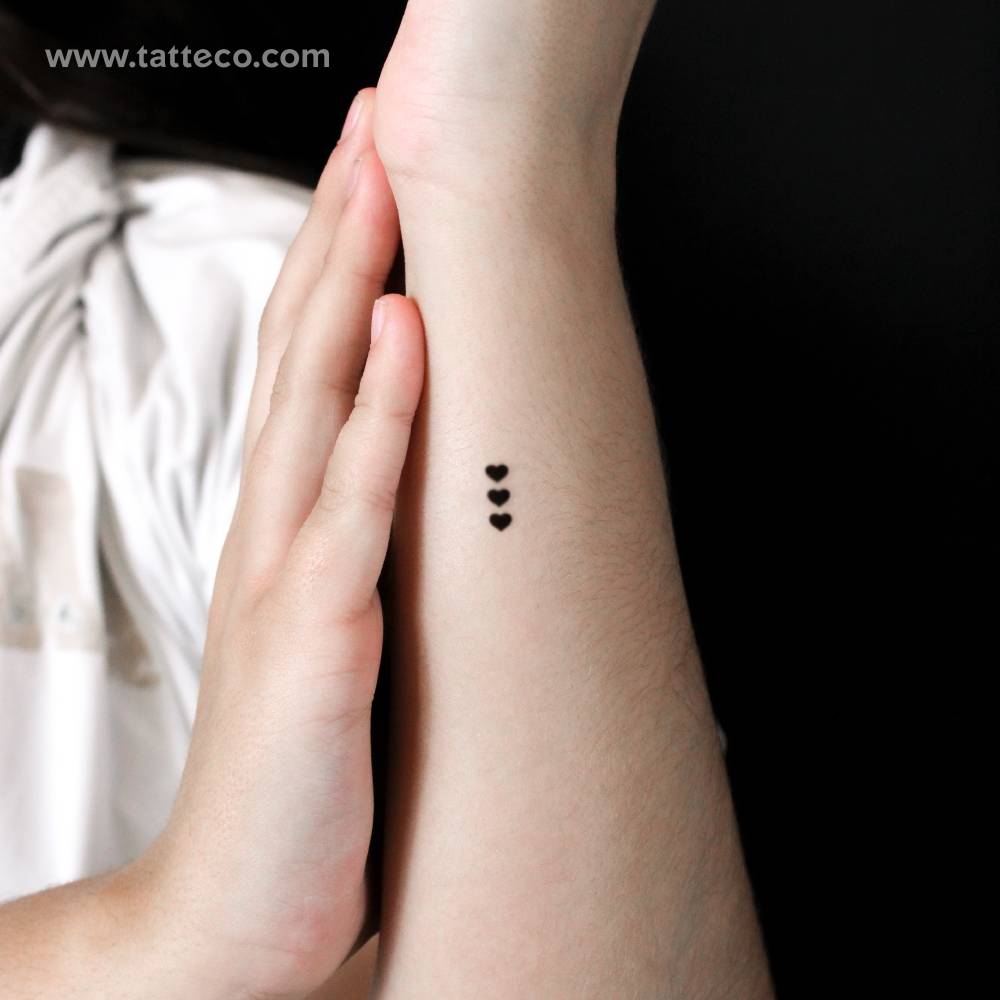 Three tiny black hearts semi-permanent tattoo located on the wrist.