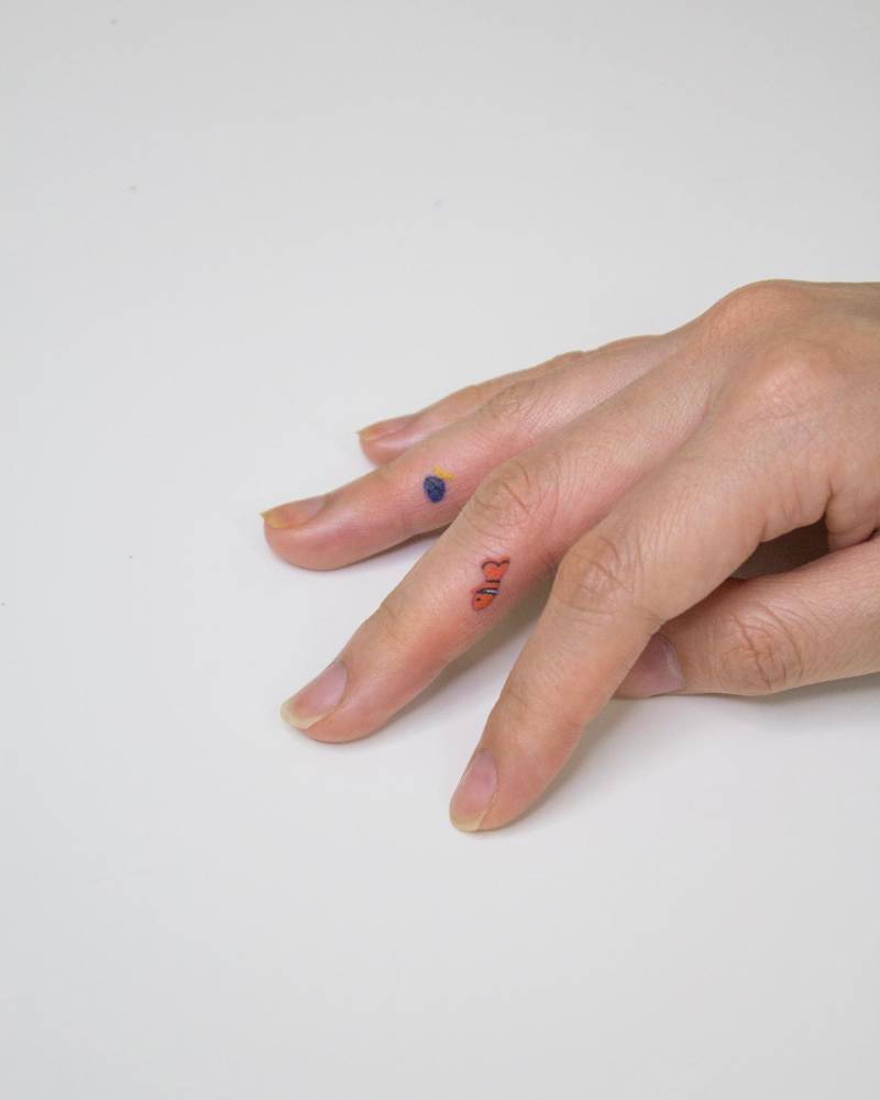 Tiny Dory and Nemo tattoo located on the fingers, minimalistic style.