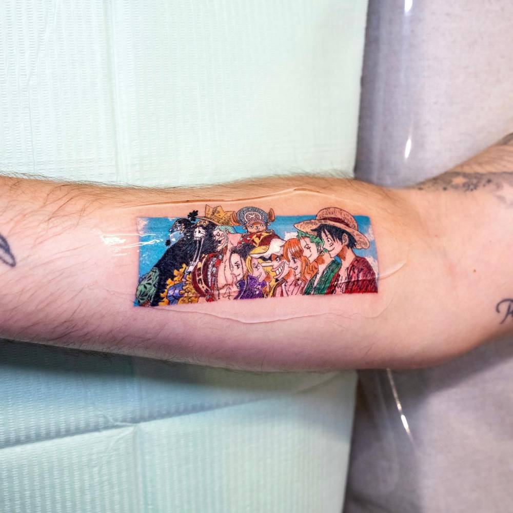 One Piece tattoo located on the inner forearm, cartoon style.