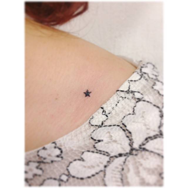 Tiny minimalistic star tattoo placed on the shoulder.