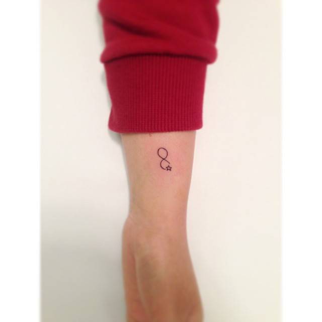 Infinity symbol and star tattoo in minimalistic style placed on the wrist.