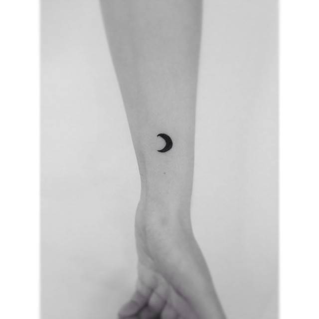 Tiny crescent moon in minimalistic style tattooed on the wrist.