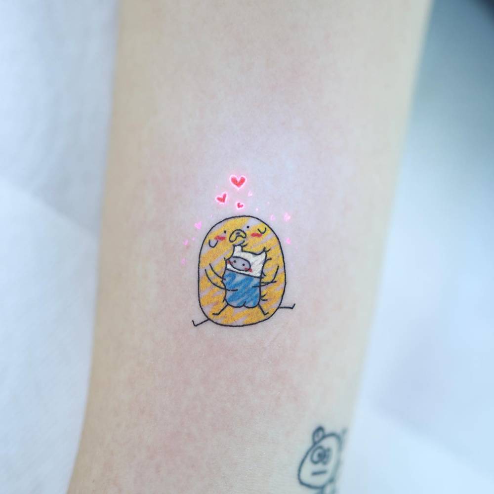 Jake and Finn tattoo in cartoon style done on the upper arm.