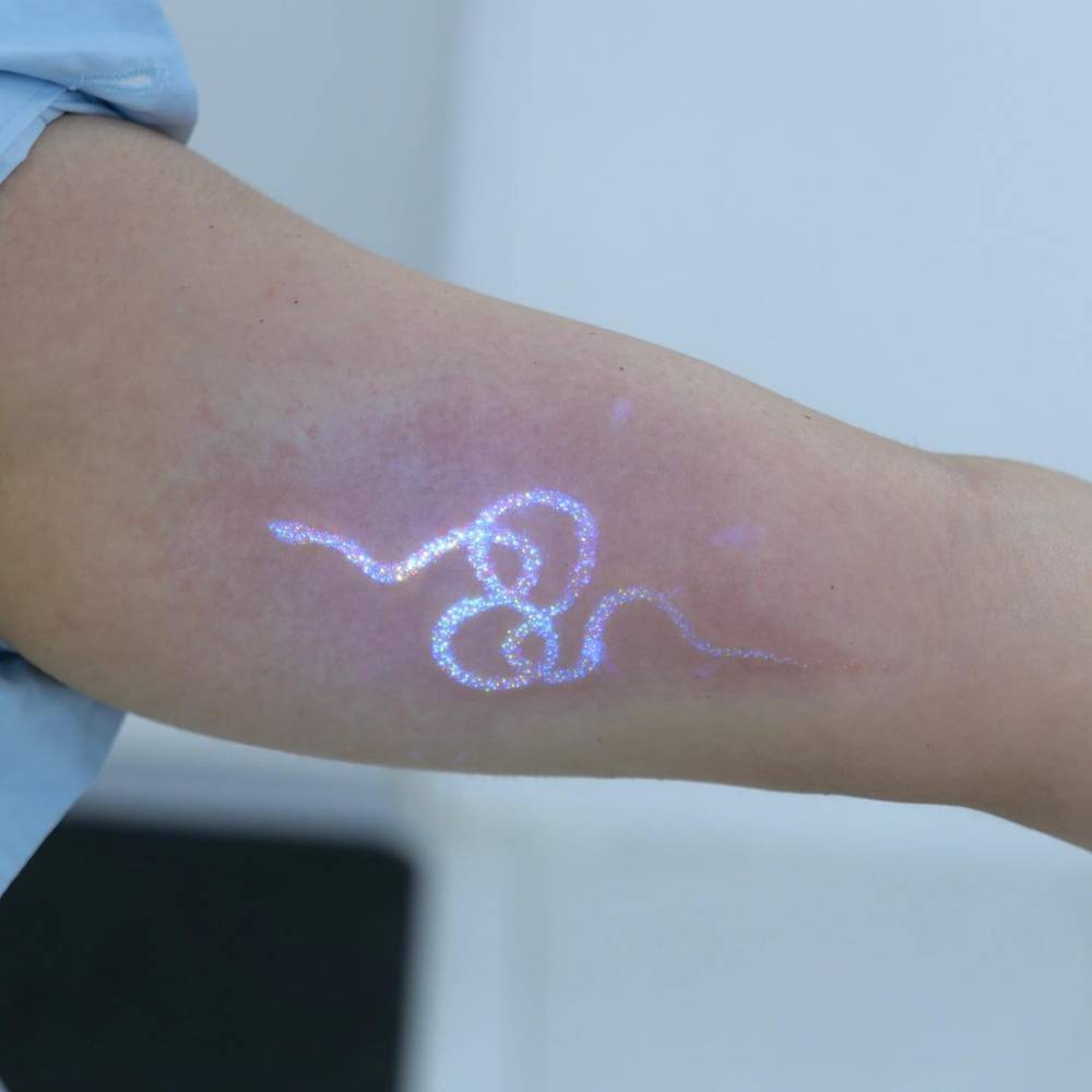 Glitter effect snake tattoo located on the inner arm.
