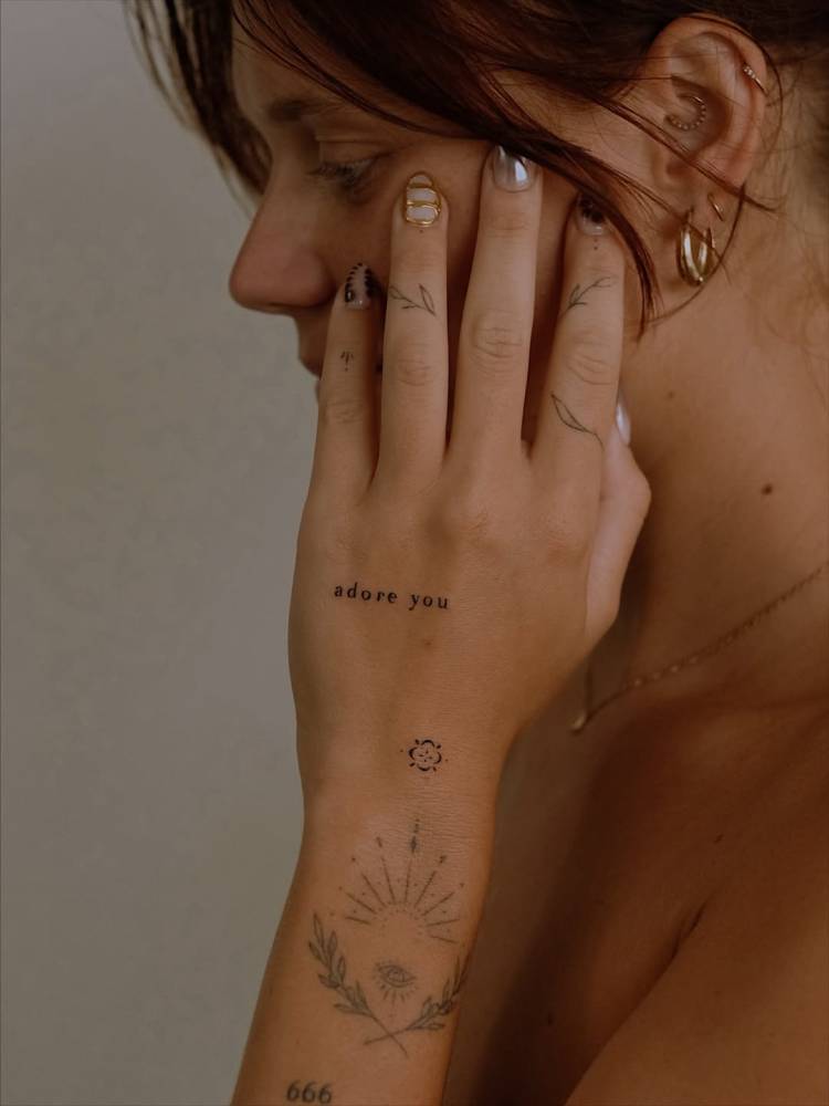 "Adore you" lettering tattoo located on the hand.