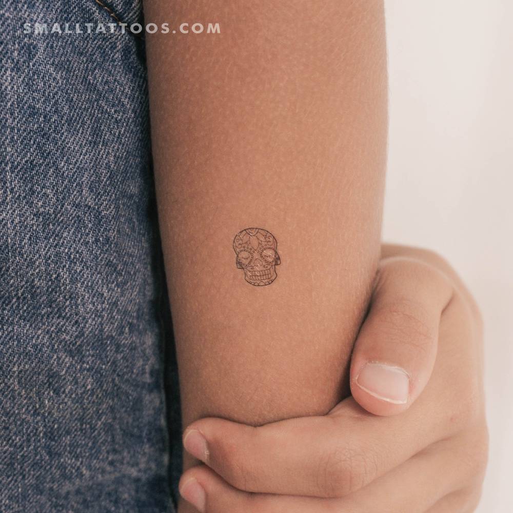 Fine line style sugar skull temporary tattoo located on the tricep.