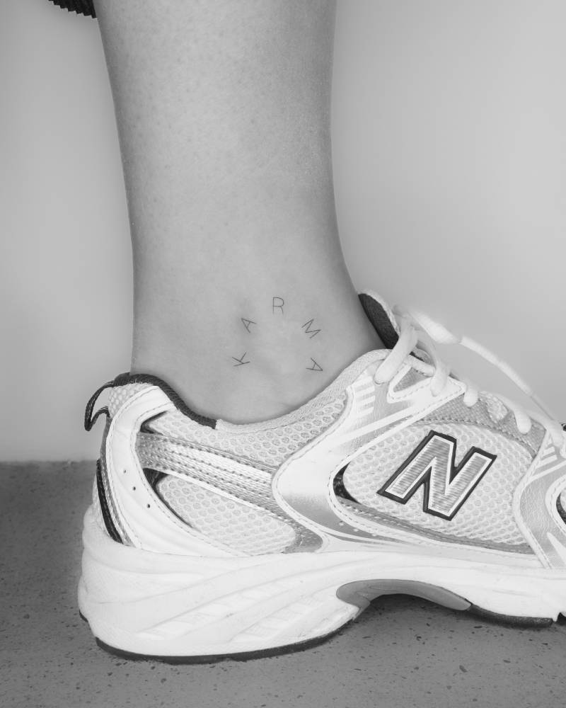 Handwritten word "karma" tattoo placed on the ankle.