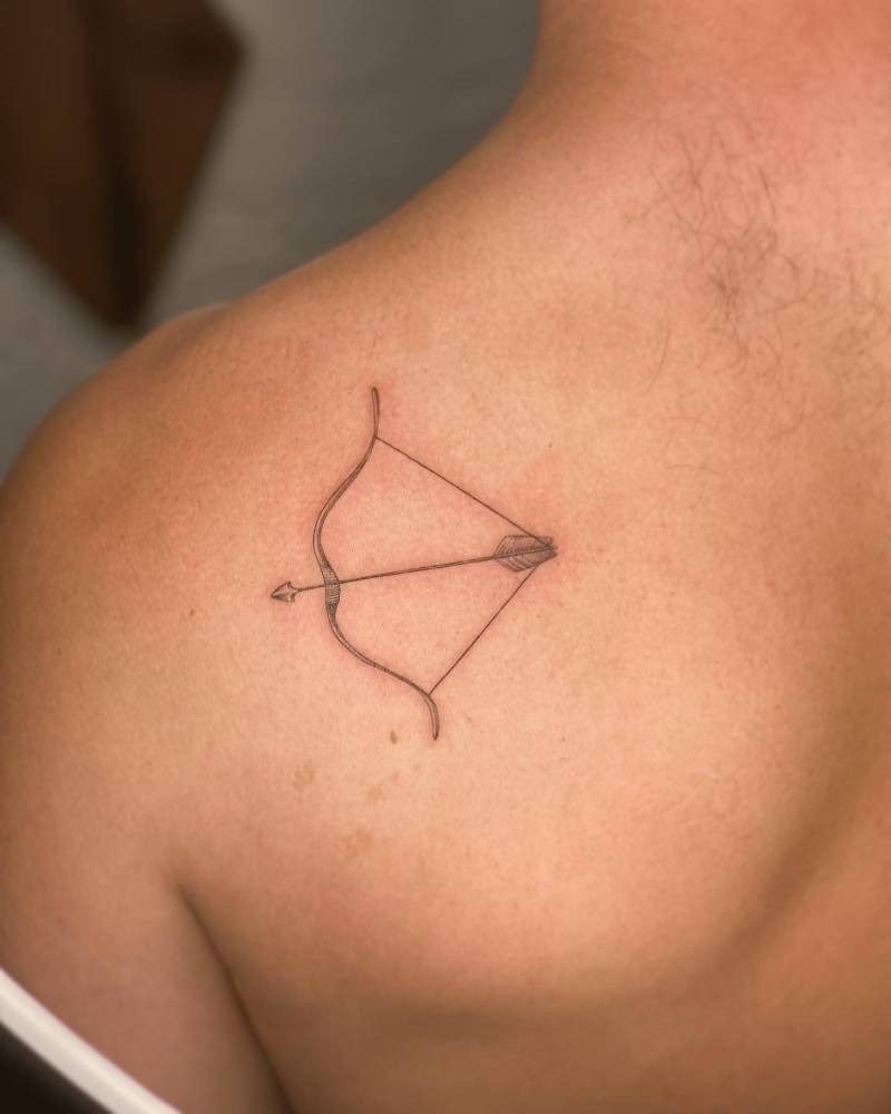 Bow and arrow tattoo in illustrative style placed on the shoulder blade.