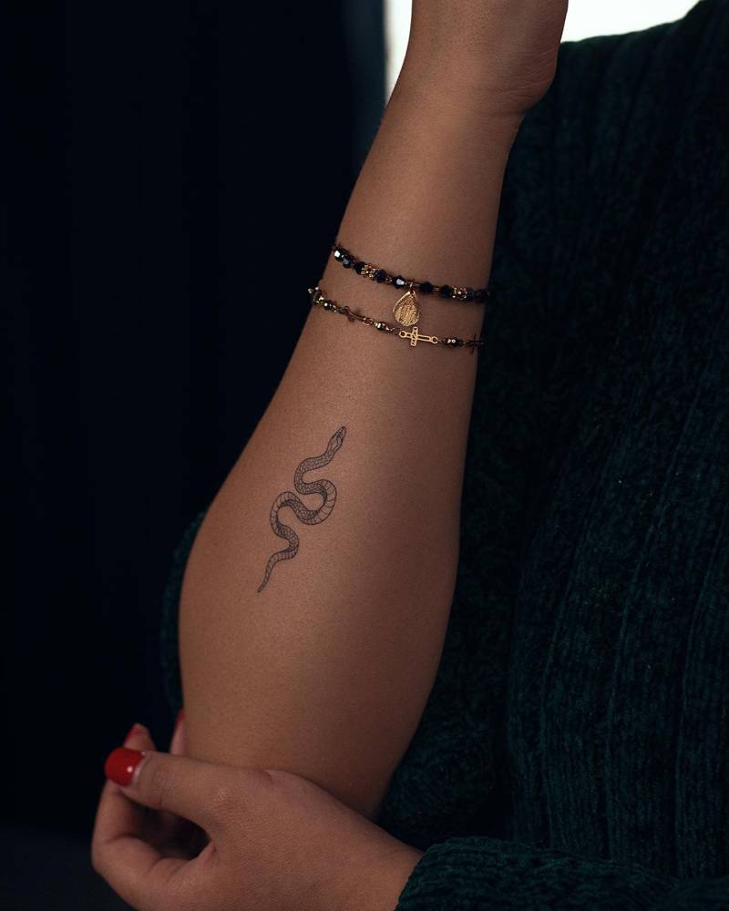 Snake tattoo in fine line style located on the forearm.