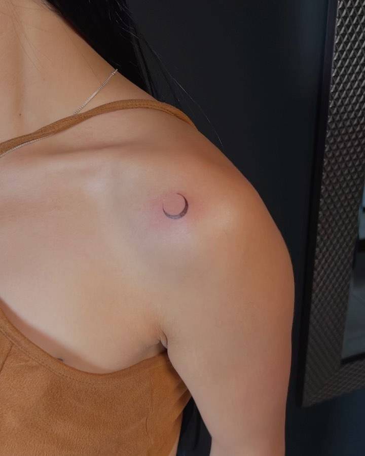 Minimalistic style crescent moon tattoo located on the shoulder.