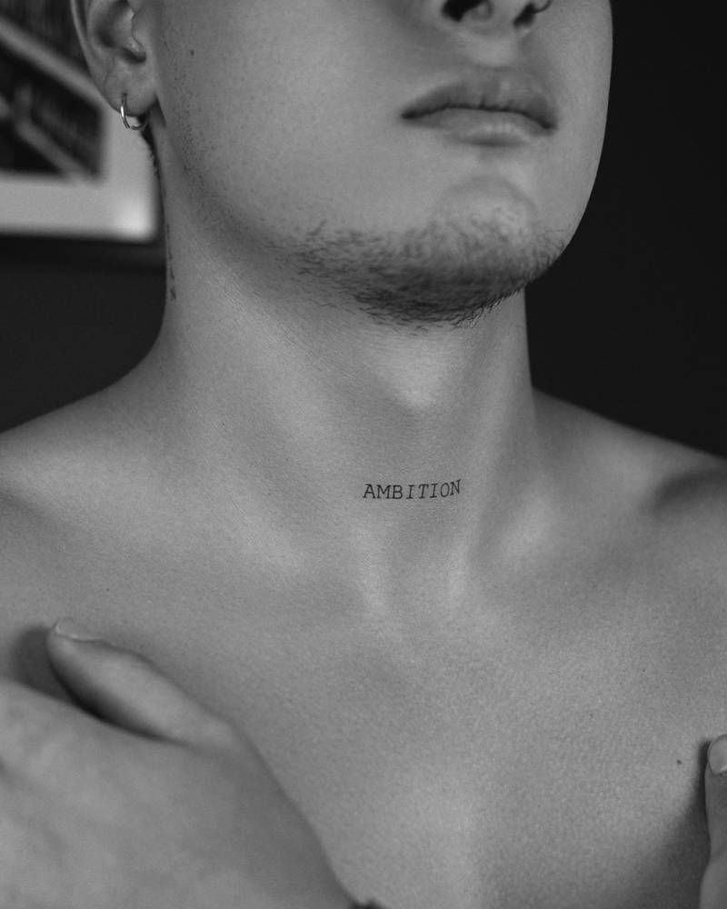 Lettering tattoo of the word "ambition" done on the throat.