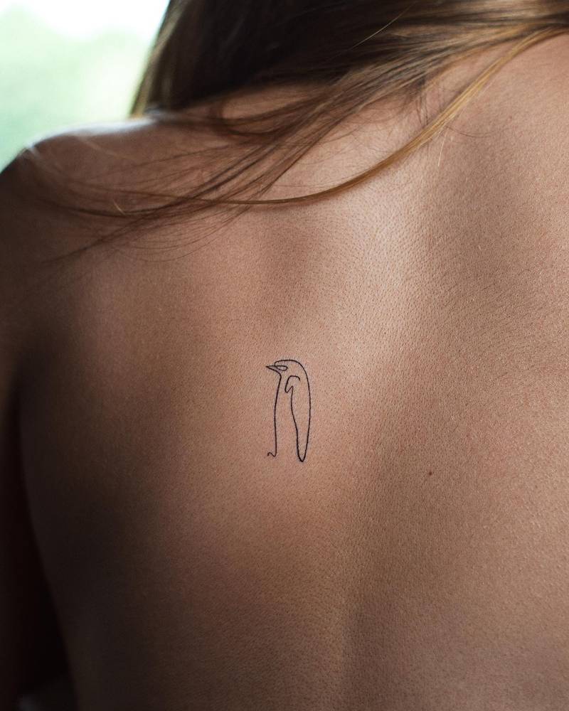 One line 'Le Pingouin' tattoo located on the back.