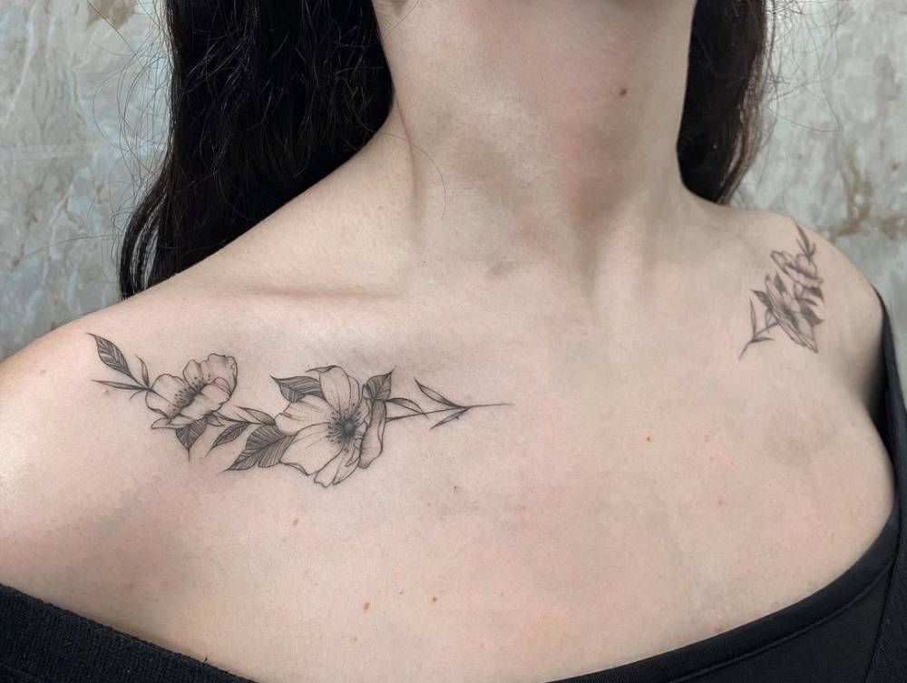 Individual matching fine line dog rose tattoos on the collarbone.