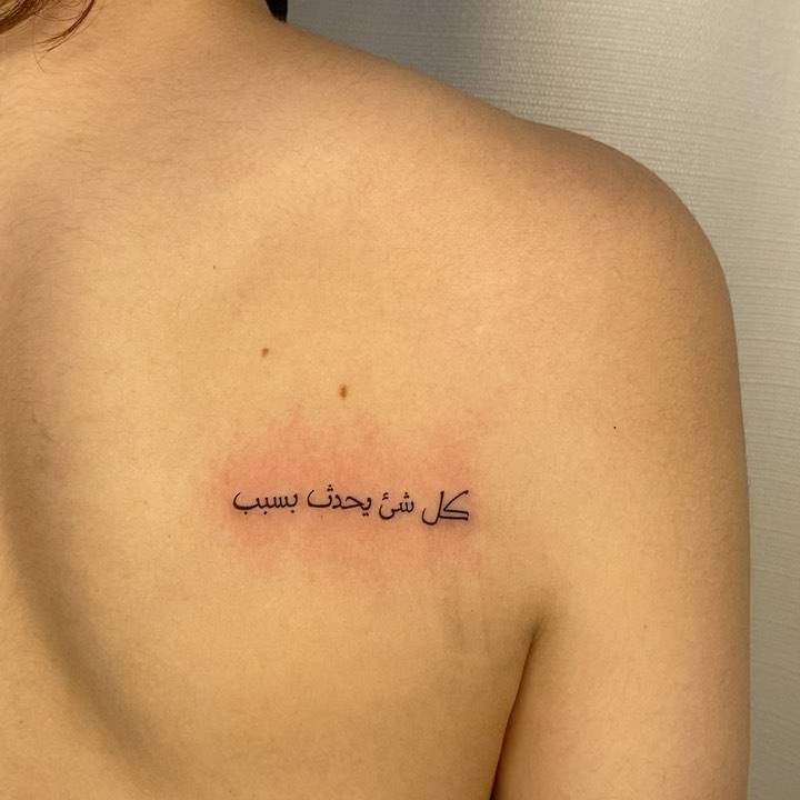 Arabic quote tattoo on the shoulder blade.