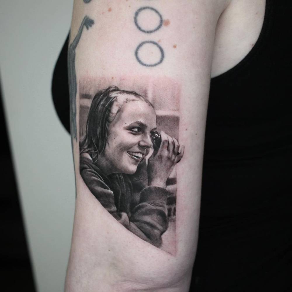Micro-realistic Britney Spears tattoo on the upper arm.